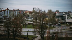 A cityscape with historic buildings, a roundabout, and a modern building with a large advertisement. - Camelia Apartament Balkon Gara (Bydgoszcz)