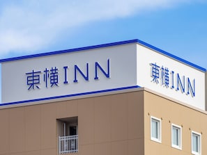 Un bâtiment portant l’enseigne « 東横INN », ce qui indique qu’il s’agit d’un hôtel.