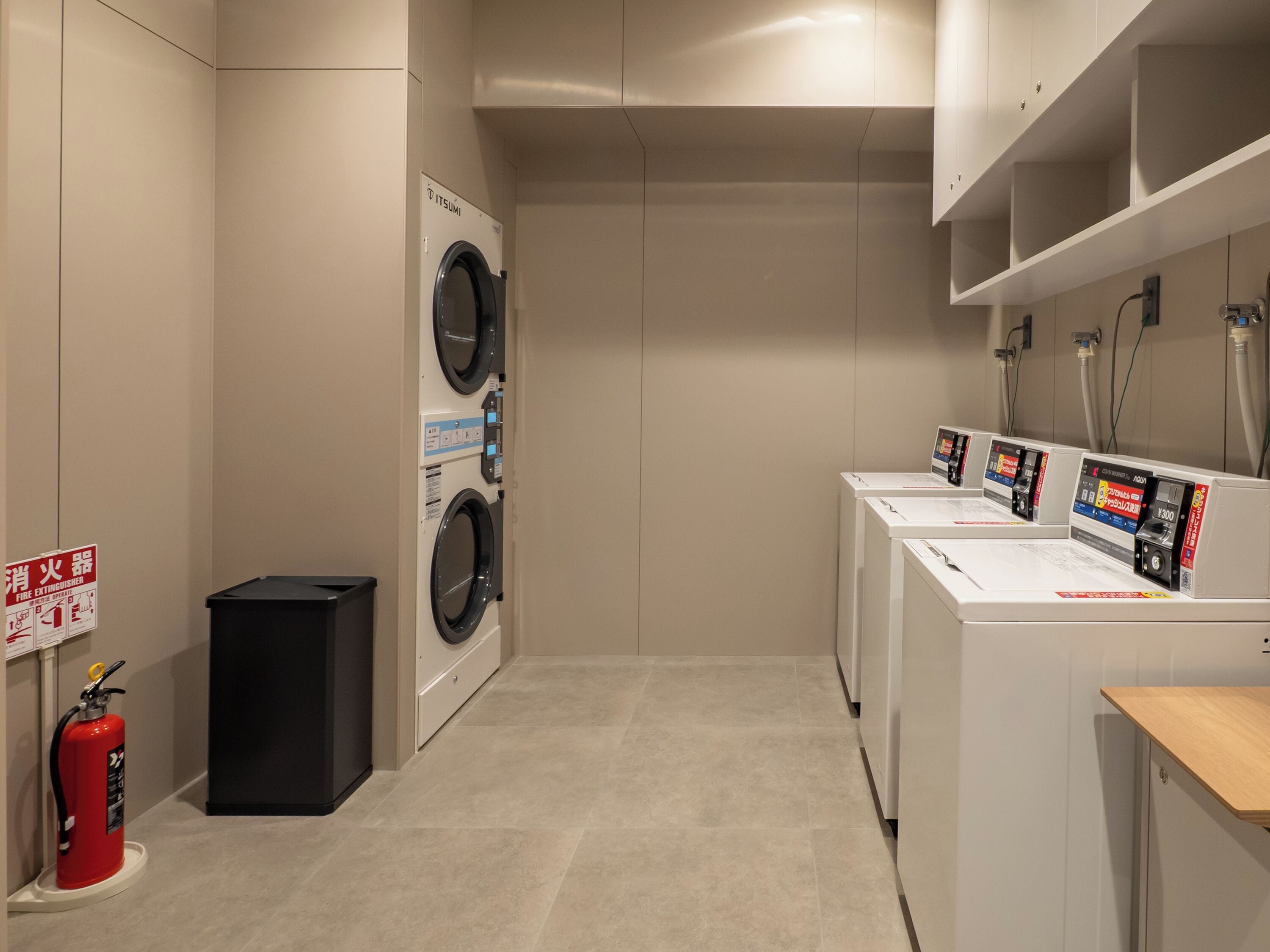 A laundry room with two washing machines, a fire extinguisher, and a water heater.
