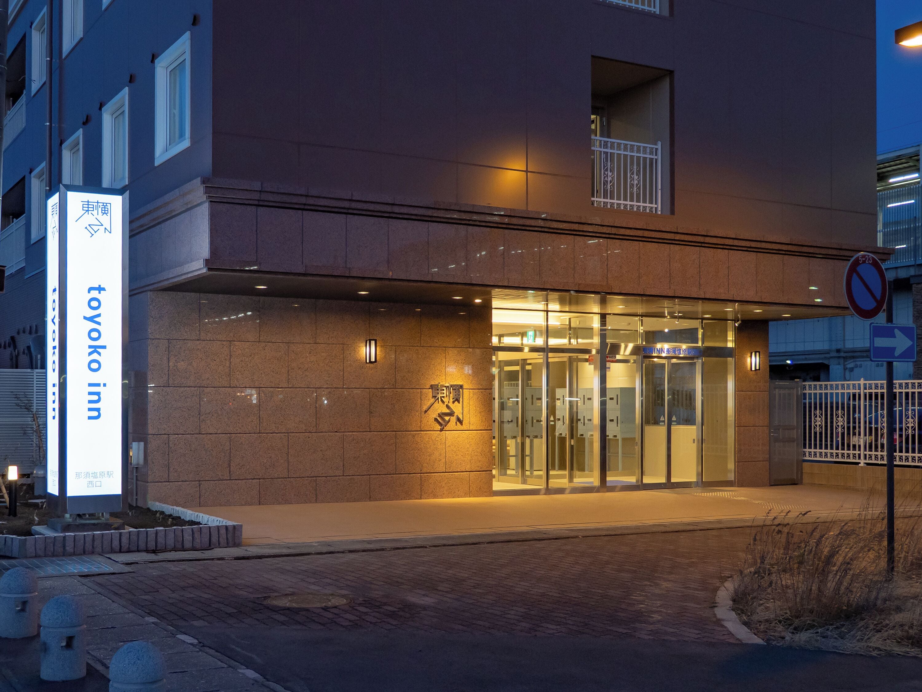 Un bâtiment avec une enseigne indiquant « Toyoko Inn » et un panneau interdisant le stationnement.