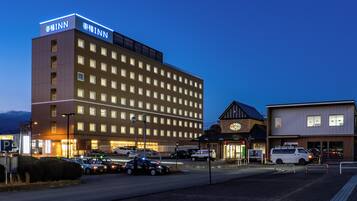 A multi-story hotel with a prominent sign, a parking lot, and a street with cars and a police vehicle.