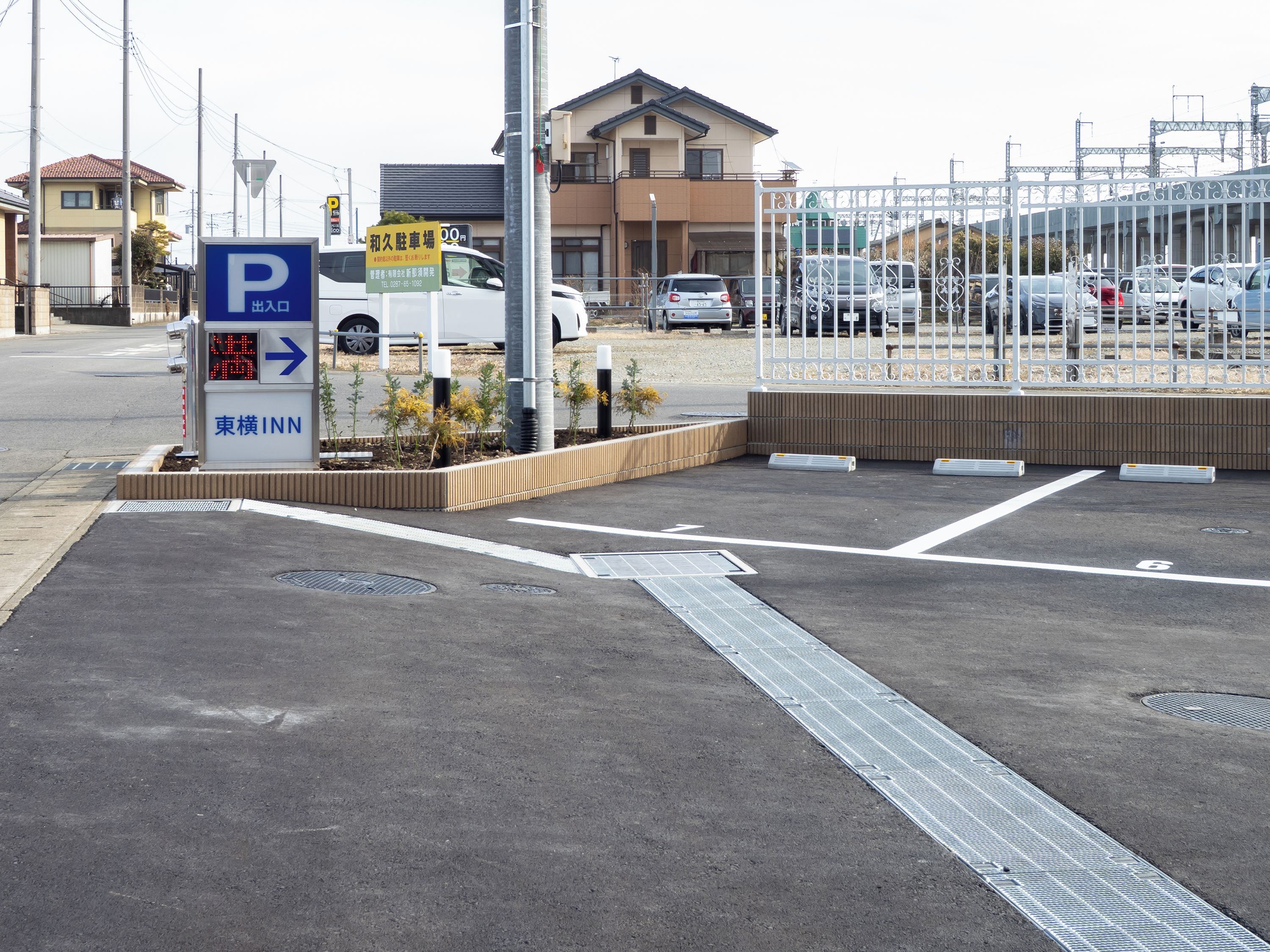 Ein Parkplatz mit Hinweisschildern, einer Fußgängerüberweg und einem verschlossenen Eingang.
