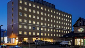 Un hotel de varios pisos con un letrero grande que dice 'INN', un estacionamiento con varios autos y un vehículo policial estacionado afuera.
