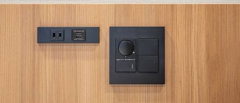A wooden panel with a black electrical outlet and a control panel with a rotary knob and two switches.