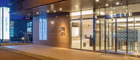 A hotel entrance with a glass facade, a reception desk, and a sign indicating 'TOYOKO INN'.