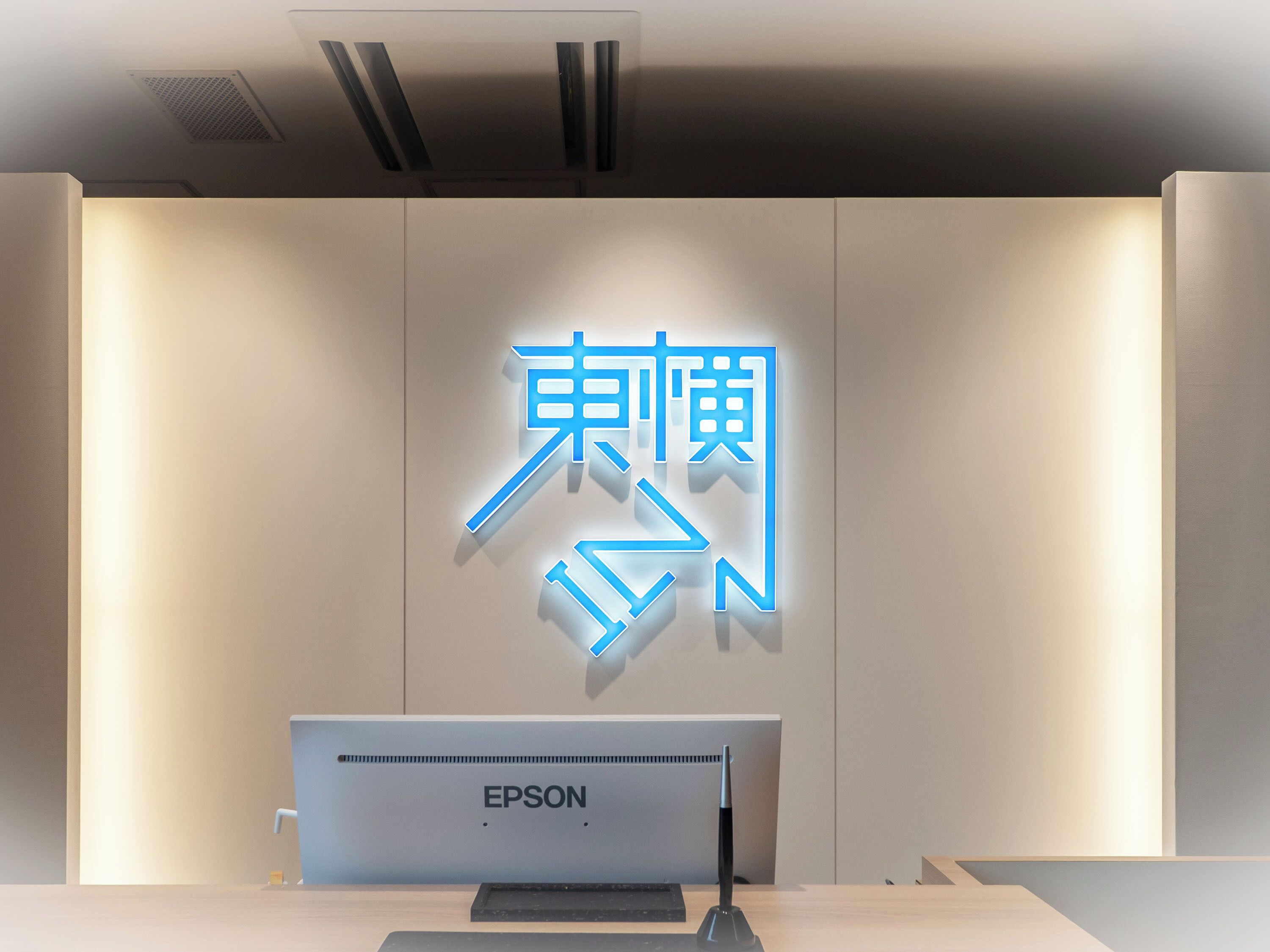 A reception desk with a large illuminated sign and an Epson printer.