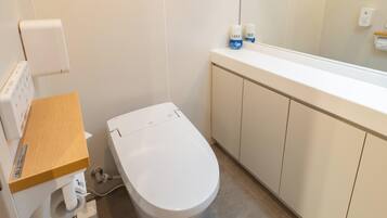 Un baño moderno con inodoro, tocador de madera, espejo y un armario blanco.