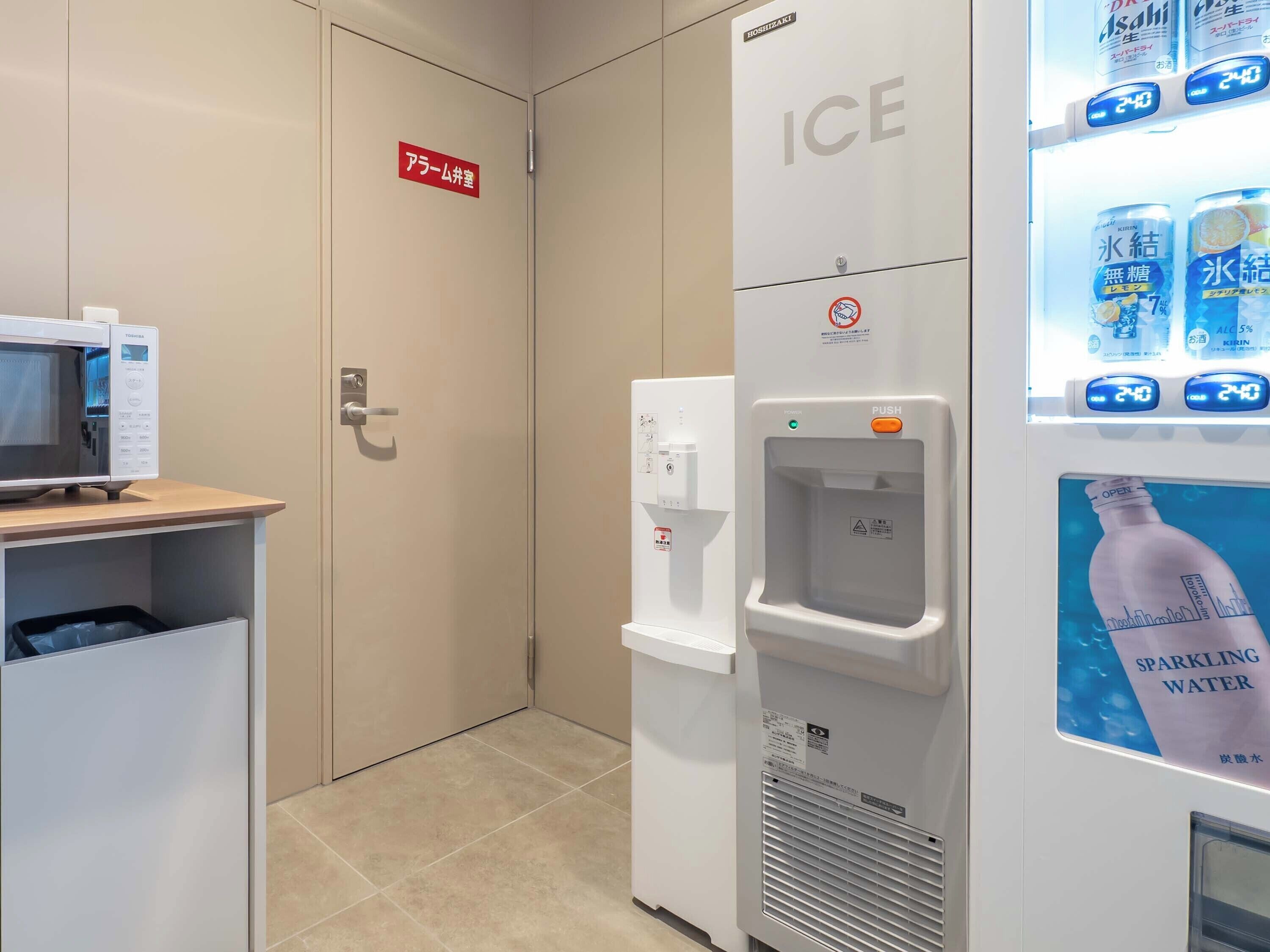 A hotel room with a minibar, an ice dispenser, and a water cooler.
