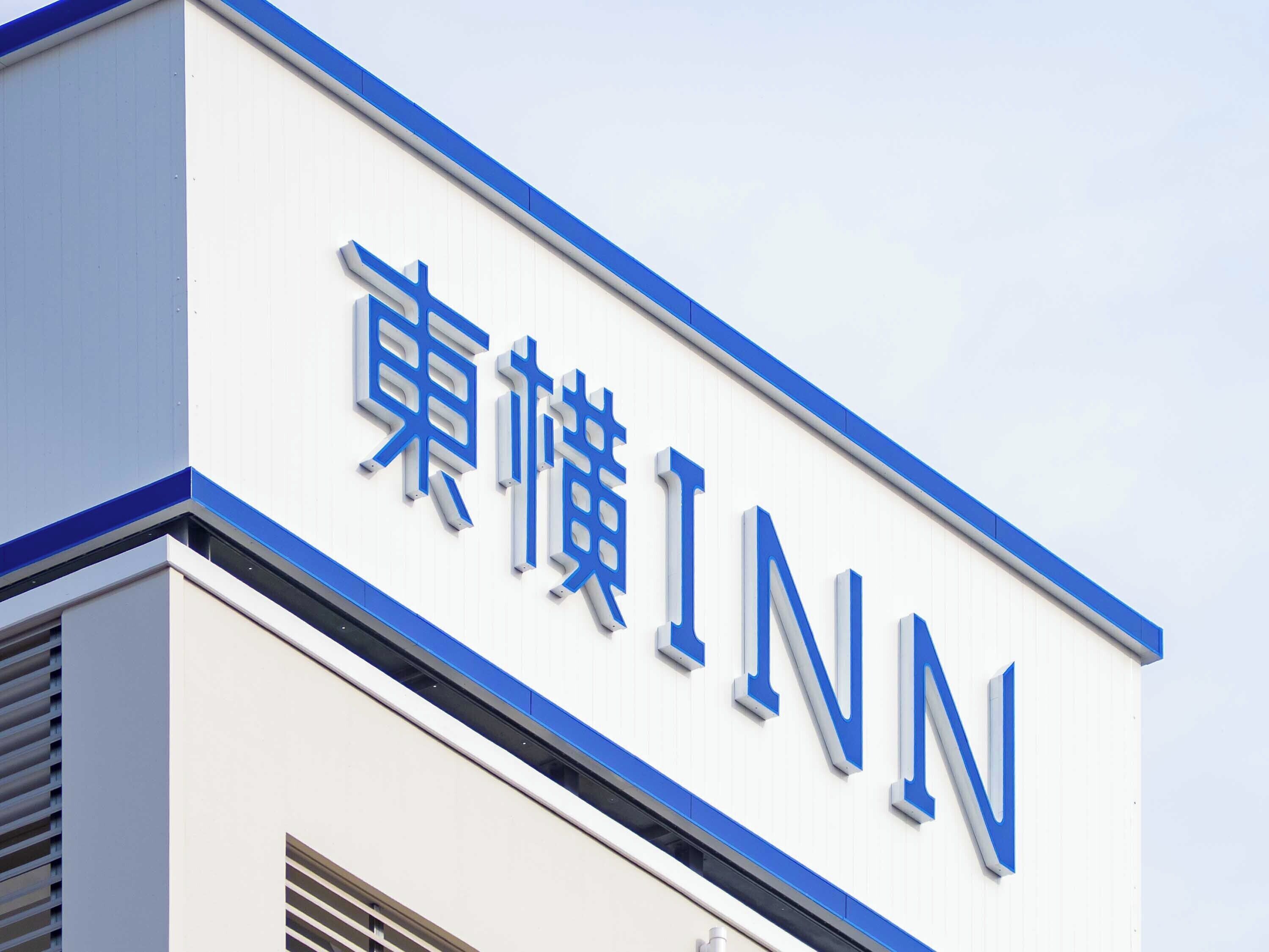 Een gebouw met een bord waarop in grote blauwe letters 'INN' staat, tegen een witte achtergrond.