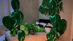 A room with a bed, balloons, and string lights.