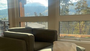 Un salon moderne doté d’une grande fenêtre donnant sur un paysage montagneux.