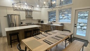 Une cuisine moderne dotée d’un îlot central, de planchers en bois et de grandes fenêtres donnant sur un paysage rocheux.