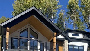Une maison moderne à deux étages, dotée d’un garage, de grandes fenêtres et d’un balcon.
