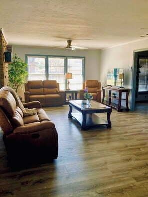 Una sala de estar con un sofá, dos sillones, una mesa de centro y un televisor.