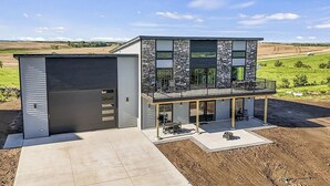 A modern two-story house with a covered patio, a garage, and a view of the countryside. - Modern Lewis and Clark lake home with lake views and 3 min drive to the beach! (Crofton)