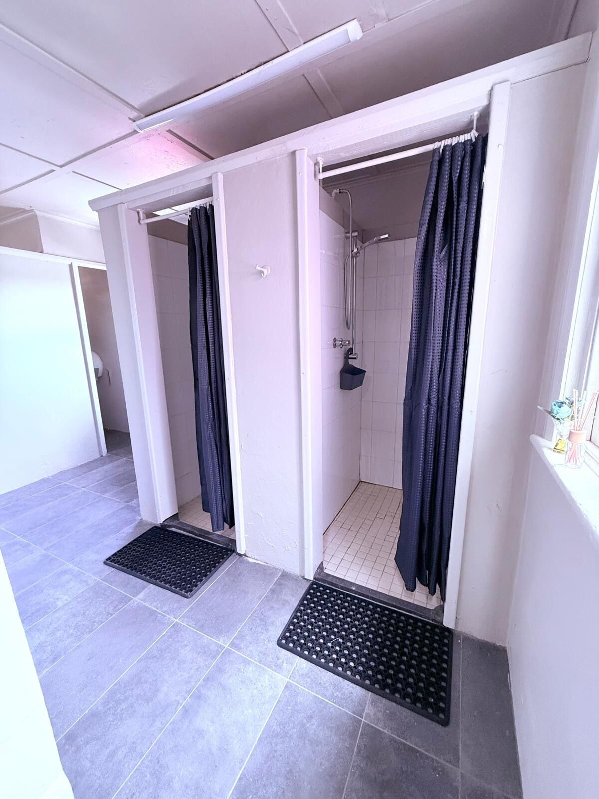 A small, enclosed shower area with a showerhead and a towel rack.