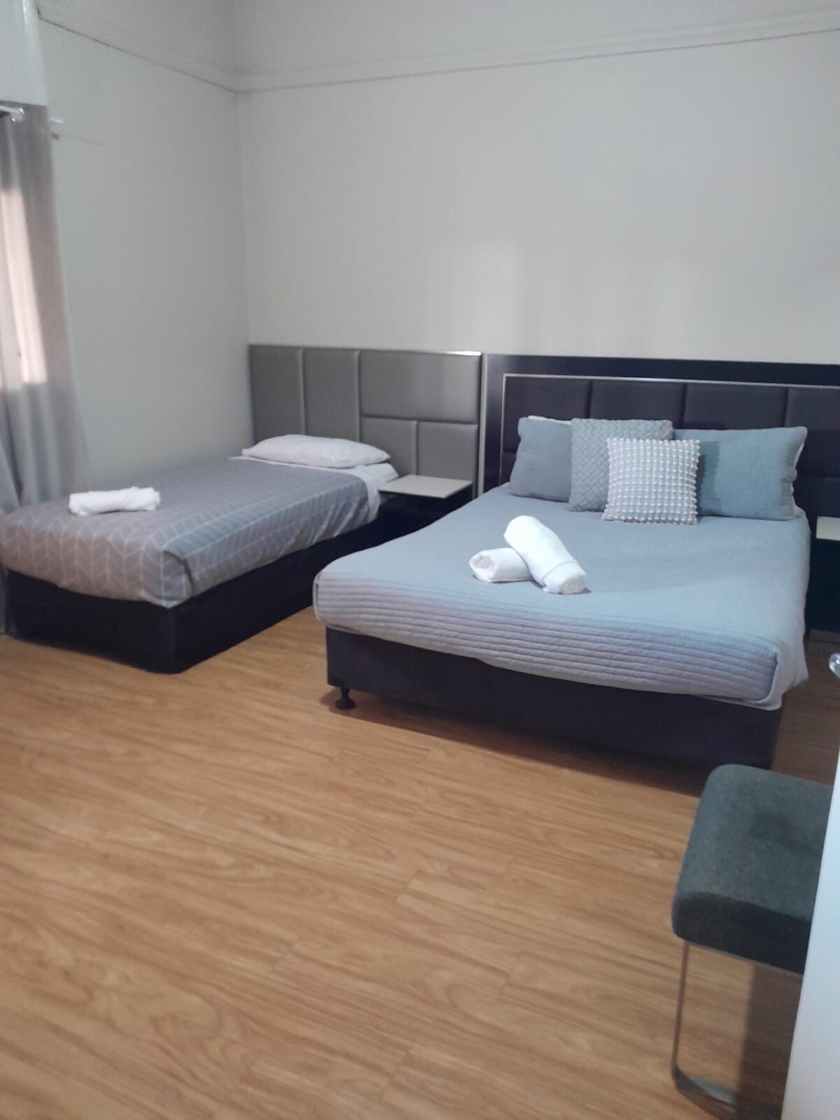 A hotel room with two beds, a wooden floor, and a small table.