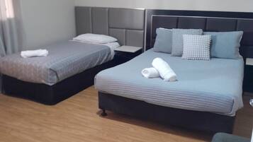 A hotel room with two beds, a wooden floor, and a small table.