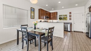 A modern kitchen with wooden cabinets, a central island, and a dining area with a table and chairs. - 4BR w hot tub, EV charger, mountain views (Flagstaff)