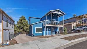 A two-story residential building with a balcony, a driveway, and a parked car. - 4BR w hot tub, EV charger, mountain views (Flagstaff)