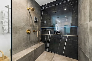 A modern bathroom with a glass-enclosed shower, a bench, and a towel rack. - The Lighthouse- Monthly 4 bd 4 bth Pool Spa (Palm Springs)