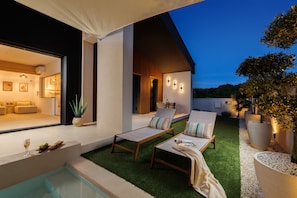 Zona d'estar exterior moderna amb dues gandules, una taula petita i una piscina.