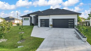 A modern two-story house with a garage, a driveway, and a well-maintained lawn. - Delightful 4-bedroom 4 full bath and one Den house with AC and heater Lehigh  (Lehigh Acres)