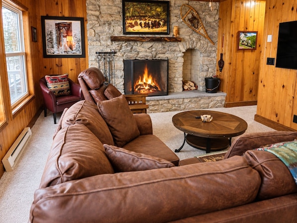 A cozy living room with a stone fireplace, leather sofa, and a round coffee table. - Stemwinder #8:Slopeside 3 Bedroom/3.5 Bath, Pool Table (Snowshoe)
