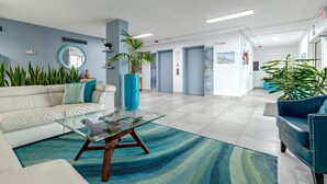 Eine moderne Lobby mit einem Glastisch, Sofas und Topfpflanzen.
