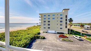 Ein Hotel mit Parkplatz, Blick auf den Strand und blauem Himmel.
