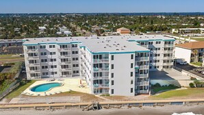 Ein mehrstöckiges Hotel mit Schwimmbad, Zugang zum Strand und Meerblick.