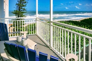 A balcony with a view of the ocean, a table with chairs, and a small garden area. - Sunny Satellite Beach 1BR Condo by the Sea W/ Private Balcony & Partial Ocean View! ☀️ (Satellite Beach)