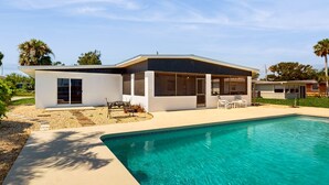 Una casa moderna con piscina, ventanas amplias y un patio.