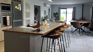 A modern kitchen with a central island, bar stools, and a dining area with a table and chairs.