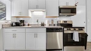 A modern kitchen with white cabinets, stainless steel appliances, and a granite countertop. - Little Italy Gem | Patio | Free Parking (Cleveland)