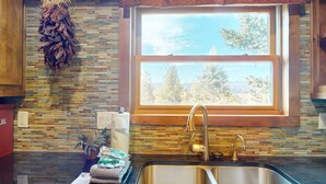 A kitchen with a window, a sink, and a backsplash. - Walk to Slopes | Master ensuite | Snowfire 303B (Angel Fire)