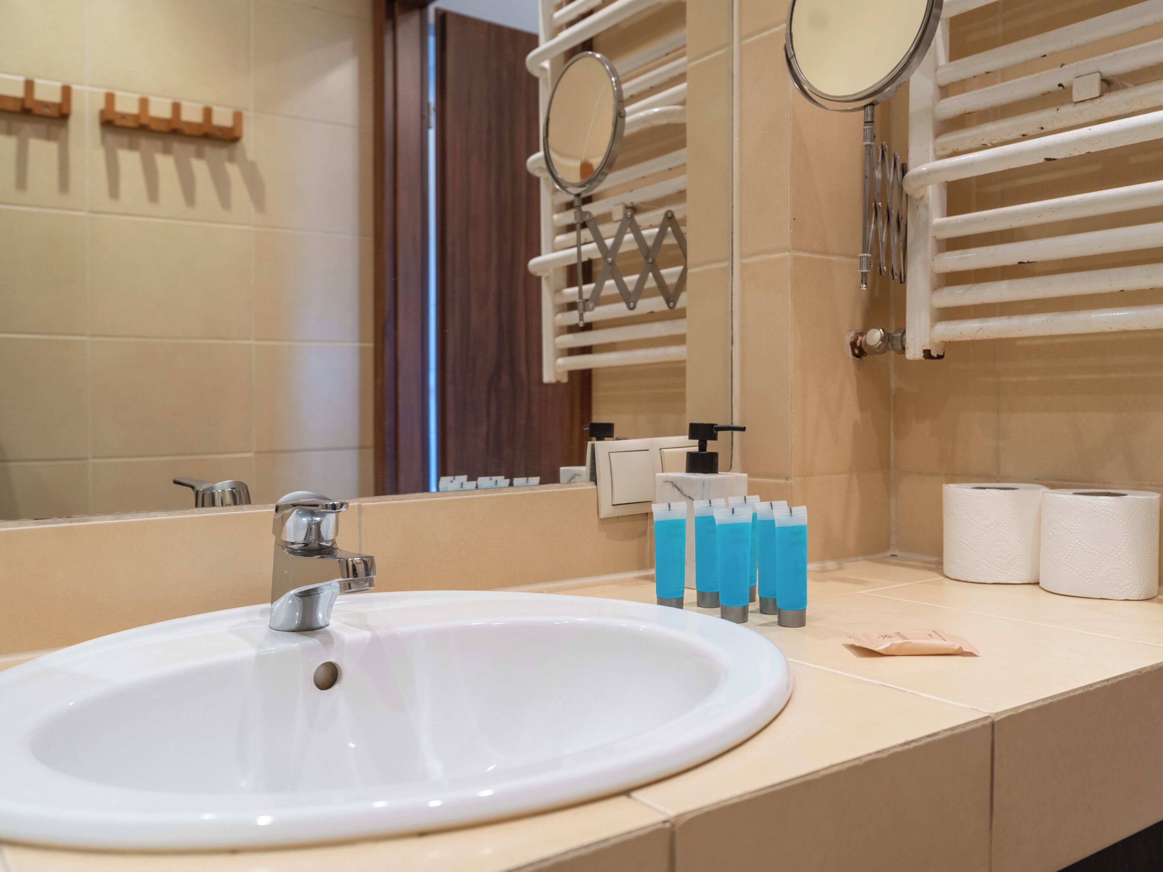 Ein Badezimmer mit einem weißen Waschbecken, zwei Spiegeln und einem Handtuchhalter.