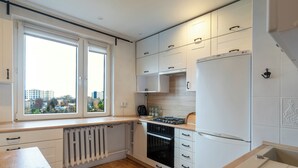 Eine moderne Küche mit weißen Schränken, einem eingebauten Backofen und einem Fenster mit Blick auf die Stadt.
