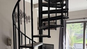 A modern interior with a spiral staircase, a dining area with outdoor seating, and a large sliding glass door.