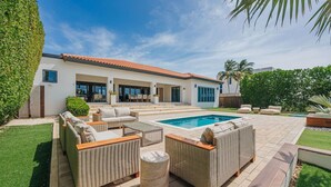 Ein modernes Haus mit Swimmingpool, Gartenmöbeln und einem gepflegten Garten.