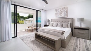 Quarto moderno com uma cama grande, uma mesa de cabeceira, um banquinho e vista para uma varanda.