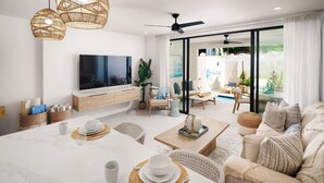 Uma sala de estar moderna com uma televisão grande, assentos confortáveis, um espaço de jantar e vista para o exterior.
