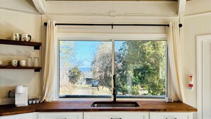 Une cuisine dotée d’une grande fenêtre, de meubles blancs et d’un plan de travail en bois.