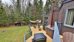 Eine Terrasse mit Sitzgelegenheit im Freien, einem Whirlpool und einem großen Fenster mit Blick auf eine bewaldete Landschaft.