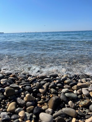 A pebbled beach with clear water and distant boats. - Cros de Cagnes, apartment with the Best Location (Cagnes-sur-Mer)