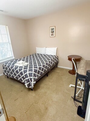 A bedroom with a bed, a chair, a small table, and a picture on the wall. - MINS TO ATRIUM HEALTH, CAROWINDS, AMP BALLANTYNE (Charlotte)