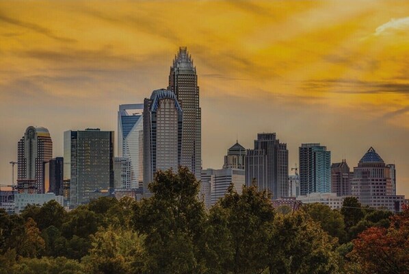 A city skyline with modern high-rise buildings and a sunset sky. - MINS TO ATRIUM HEALTH, CAROWINDS, AMP BALLANTYNE (Charlotte)