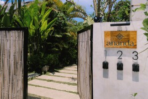 A gated entrance with a wooden sign reading 'ananda' and mailbox numbers 1 to 3.