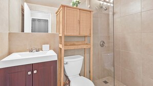 Un bagno con un armadietto in legno, un WC, un lavandino e una doccia.