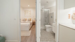 Een moderne hotelkamer met een bed, nachtkastje en een badkamer met douche, toilet en wastafel.